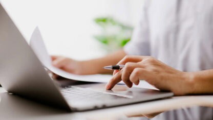 Professional inputting expenses on laptop computer