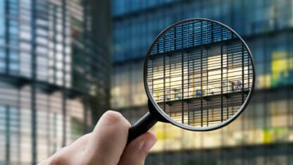 A magnifying glass behind held up to an office building.