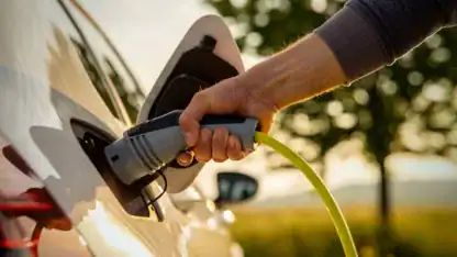 Man inserts a power cord into an electric vehicle (EV) for charging